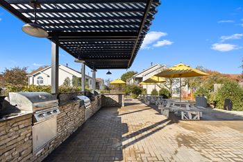 A patio with a barbecue grill and tables with umbrellas