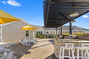 A patio with a barbecue grill and tables with umbrellas