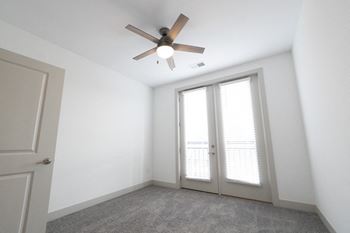 A bedroom with white walls and a ceiling fan