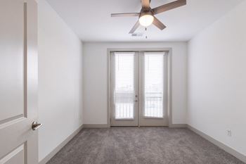 A bedroom with white walls and a ceiling fan