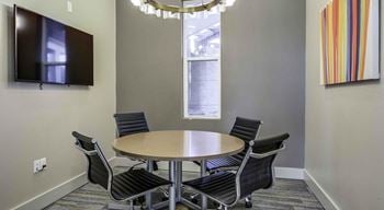 A conference room with a table, chairs, and a television.