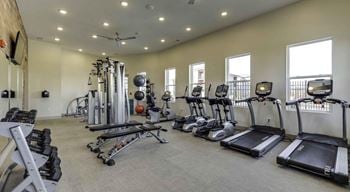 A spacious gym with a variety of equipment including treadmills, elliptical machines, and weight machines.