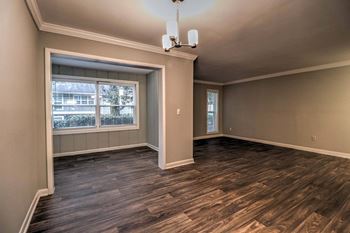 An empty living room with wood floors and a window