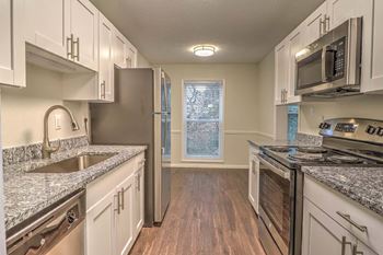 A kitchen with granite counter tops and white cabinets