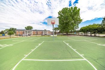 A basketball court with a hoop and a building in the background.