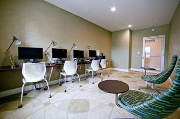 A room with a desk, chairs, and a computer.