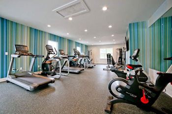 A gym with a variety of exercise equipment including treadmills, stationary bikes, and elliptical machines.