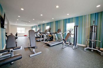 A gym with a variety of equipment including treadmills, weights, and exercise machines.