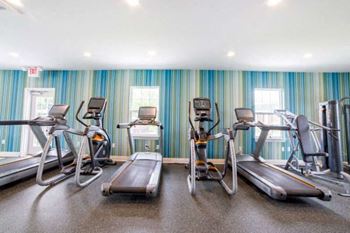A gym with treadmills, stationary bikes, and elliptical machines.