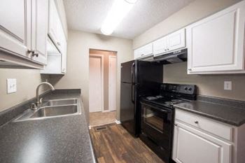 A kitchen with a black refrigerator and white cabinets.