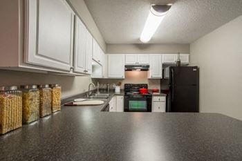 A kitchen with black countertops and white cabinets.