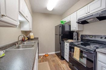 A kitchen with black appliances and white cabinets.
