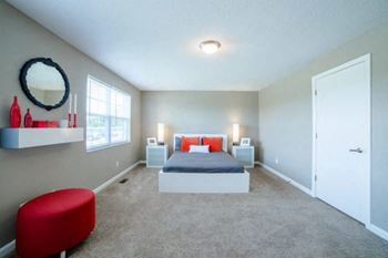 A bedroom with a bed, nightstands, and a red chair.