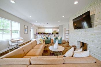A living room with a tan couch and a fireplace.