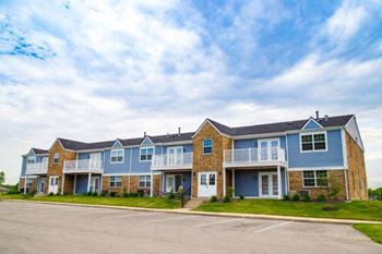 A large apartment complex with a parking lot in front.