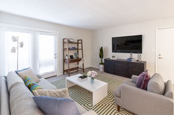 A living room with a grey couch, a white coffee table, and a television on a cabinet.