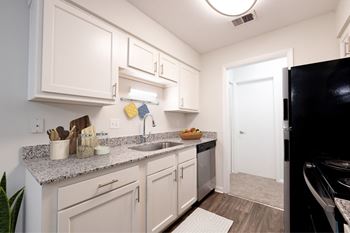 A kitchen with white cabinets and a black refrigerator.