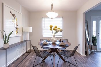 A dining room with a table set for two and a vase of yellow flowers.