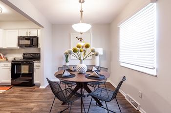 A kitchen with a table set for two and a vase of flowers on the table.