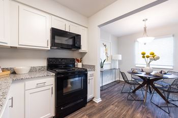 A black stove and microwave in a white kitchen.