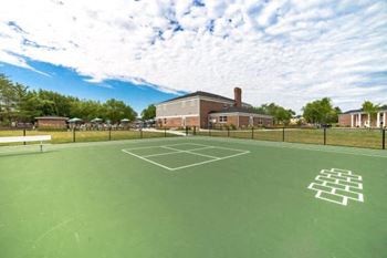 A tennis court with a white line in the middle and a building in the background.