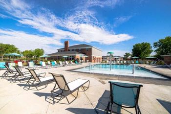 A pool area with chairs and a building in the background.