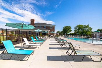 A sunny day at the pool with chairs and umbrellas.