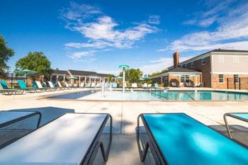 A sunny day at the pool with blue loungers and a green umbrella.