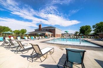 A pool area with sun loungers and a building in the background.
