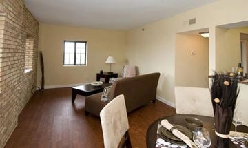 Indianapolis apartment for rent - A living room with a brown couch, a coffee table, and a dining table set for two.