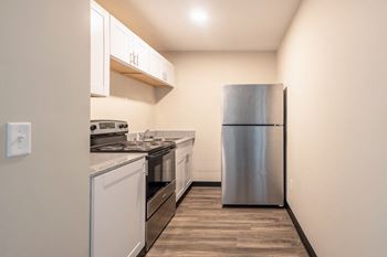 A kitchen with white cabinets and stainless steel appliances and a refrigerator