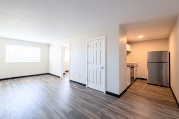 The living room and kitchen of a new home with a stainless steel refrigerator