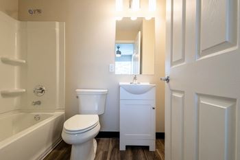 A bathroom with a toilet sink and tub and a mirror