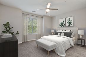 Conyers apartment for rent - A bedroom with a large bed, a ceiling fan, and a plant on a table.