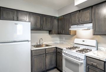 Philadelphia apartment for rent - A kitchen with a white fridge, white stove, and dark wood cabinets.
