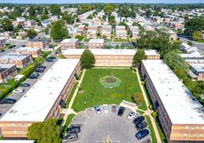 Philadelphia apartment for rent - A large building complex with a green lawn in the middle and a parking lot in front.