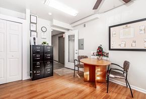 Philadelphia apartment for rent - A room with a round table and chairs, a cabinet, and a wall with a clock and pictures.