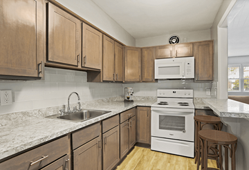 Oreland apartment for rent - A kitchen with wooden cabinets and a white stove top oven.