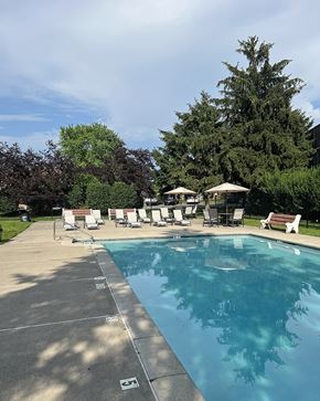 Allentown apartment for rent - A large swimming pool surrounded by trees and lounge chairs.
