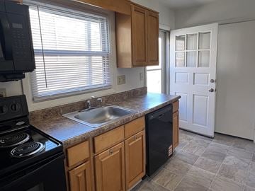 Lemoyne apartment for rent - A kitchen with a black stove top oven, wooden cabinets, and a black dishwasher.