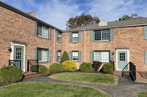 Horseheads apartment for rent - A brick building with green shutters and bushes in front.