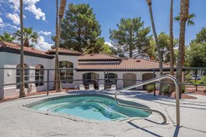 Las Vegas apartment for rent - A pool surrounded by palm trees and a building in the background.