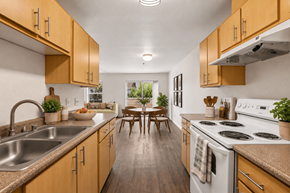 Vancouver townhouse for rent - A kitchen with wooden cabinets and a white stove top oven.