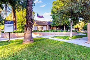 Reseda apartment for rent - an flag flies in front of a building with a sidewalk and a tree
