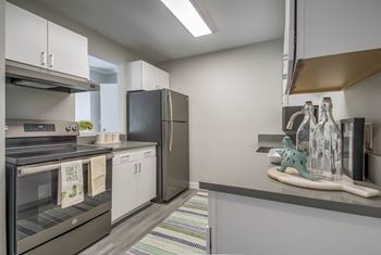 A kitchen with white cabinets and a stainless steel refrigerator