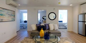 Oakland apartment for rent - A modern living room with a grey couch and a glass coffee table.