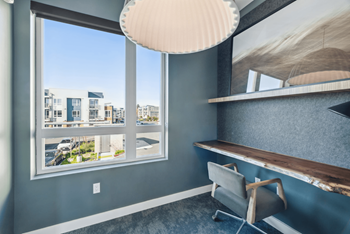 A room with a large window overlooking a street with buildings.