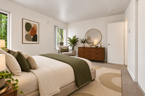 Seattle apartment for rent - A bedroom with a large bed and a round mirror on the dresser.