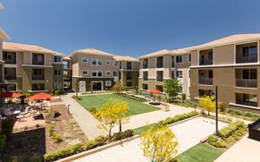 Antioch apartment for rent - an outdoor area with grass and tables and umbrellas in an apartment complex