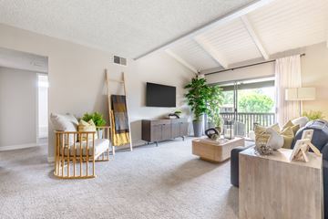 Cypress apartment for rent - A living room with a wooden chair and a flat screen TV mounted on the wall.